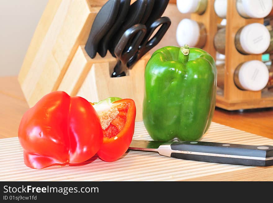 An image of red and green peppers to be cut on a chopping board. An image of red and green peppers to be cut on a chopping board.