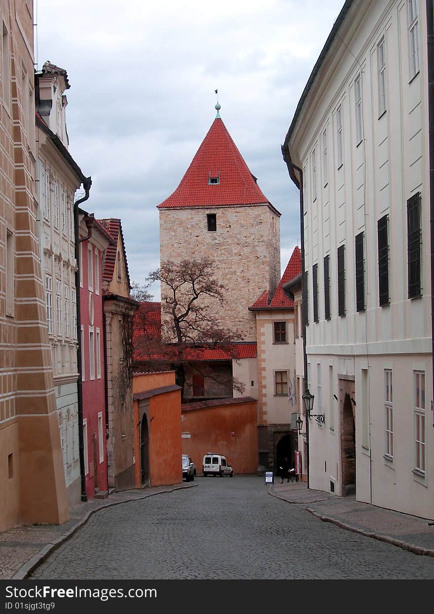 Streets of Prague. Czechia. Tower with a red, peaked roof on a background of the blue sky