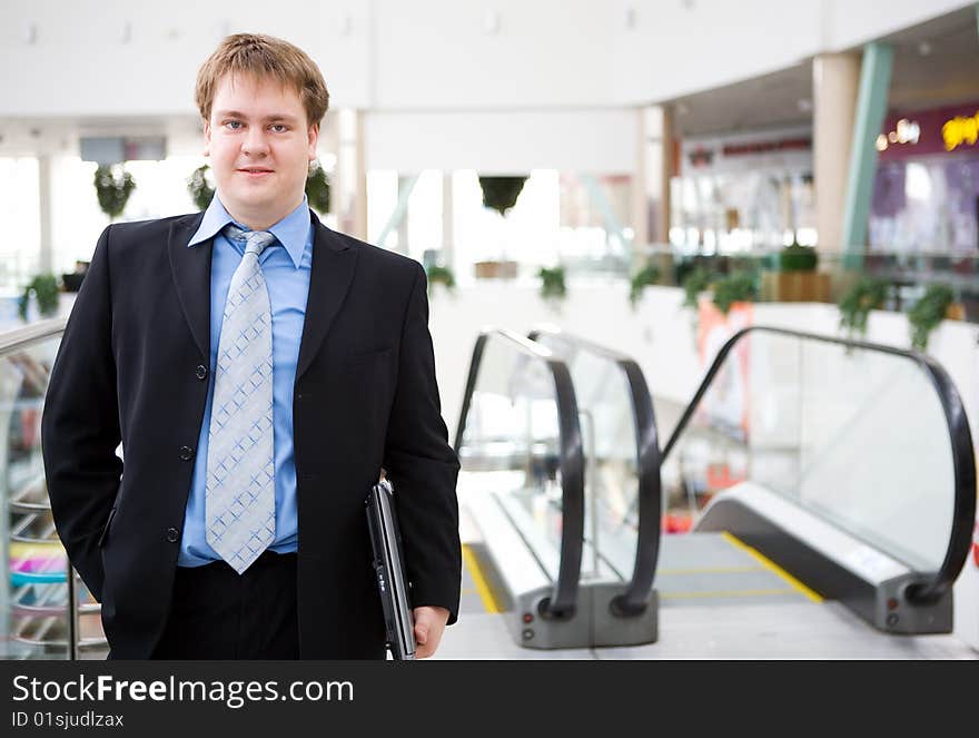 Happy young businessman with laptop in business building