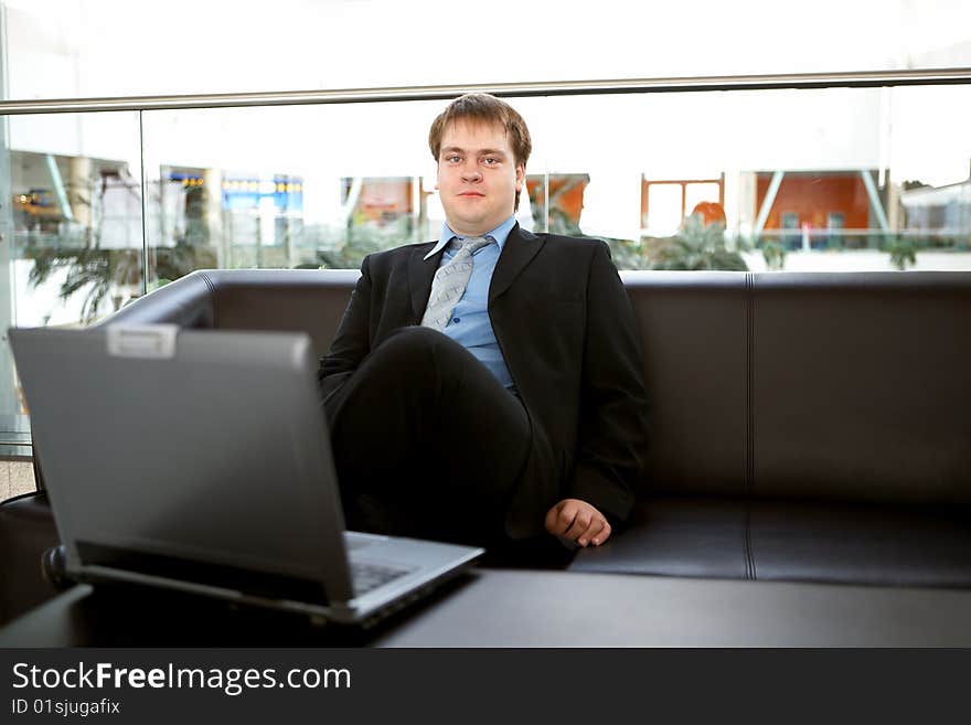 Happy young businessman with laptop in business building