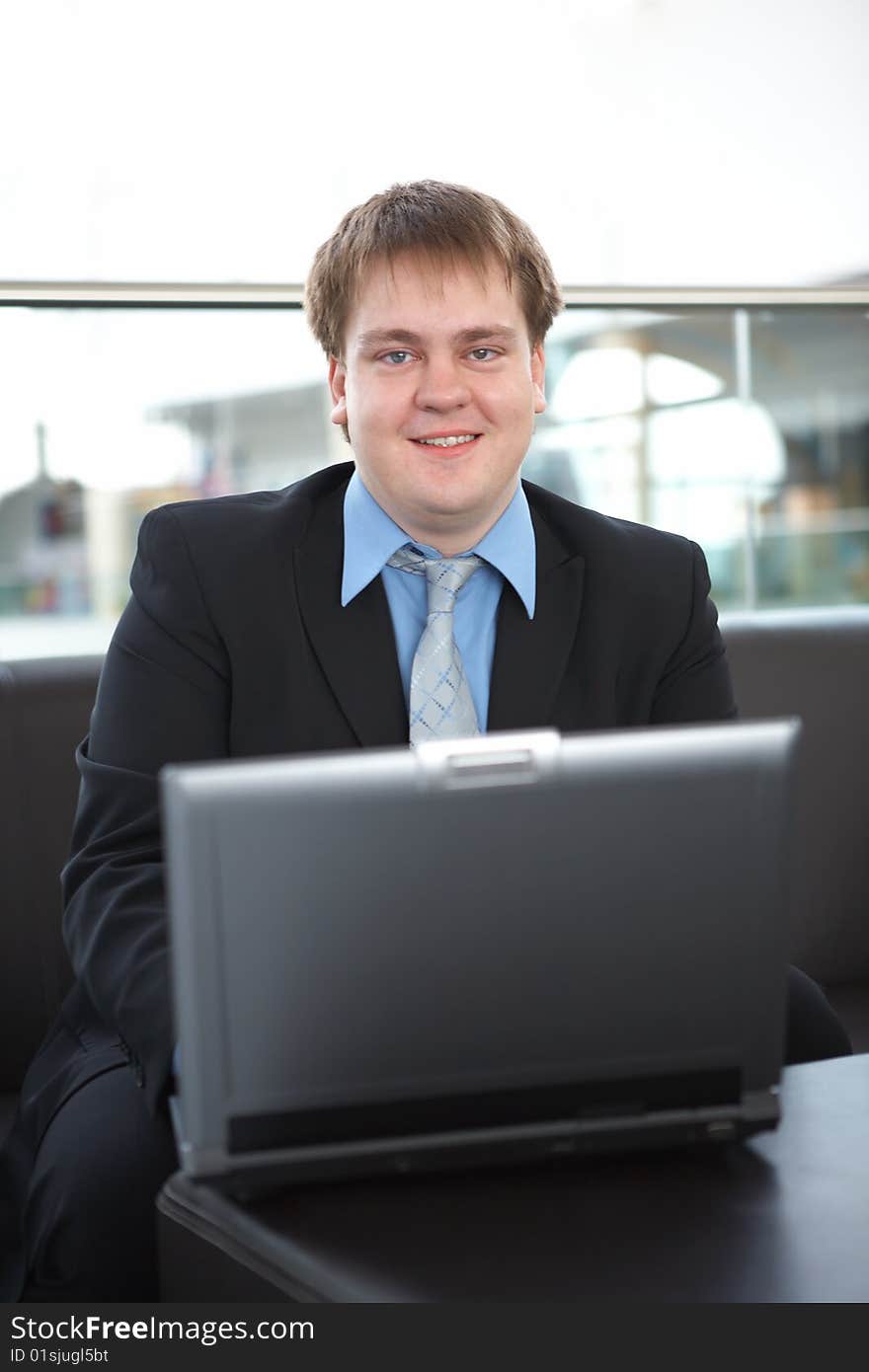 Happy young businessman with laptop in business building