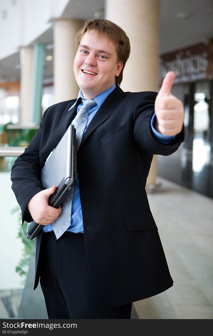 Happy young businessman with laptop in business building