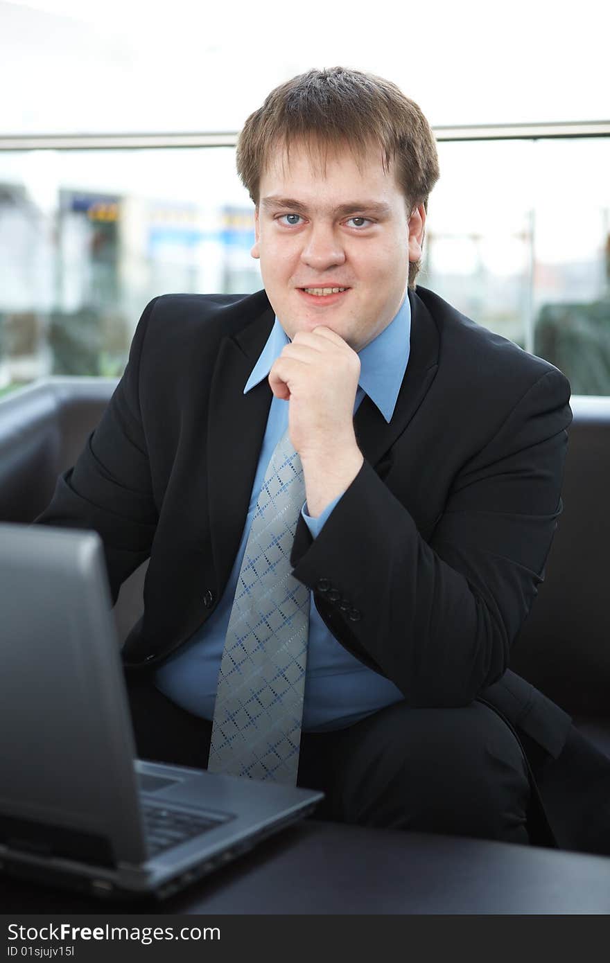 Happy young businessman with laptop in business building