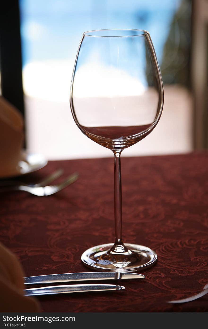 Empty wine glass on a red tablecloth and blue background. Empty wine glass on a red tablecloth and blue background