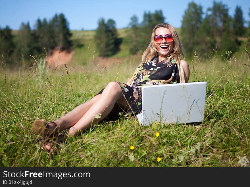 The girl sits at the laptop on the nature. Out of town.