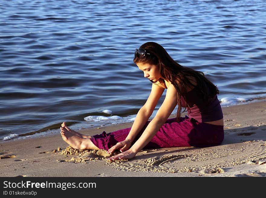 beautiful girl playing in sand on beach at sunset. beautiful girl playing in sand on beach at sunset