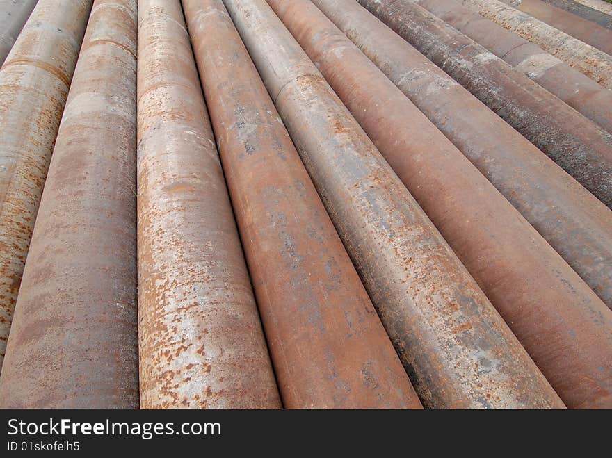 A group of large cast iron pipes lie in parallel after being used in a river dredging operation.