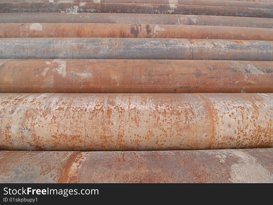 A group of large cast iron pipes lie in parallel after being used in a river dredging operation.