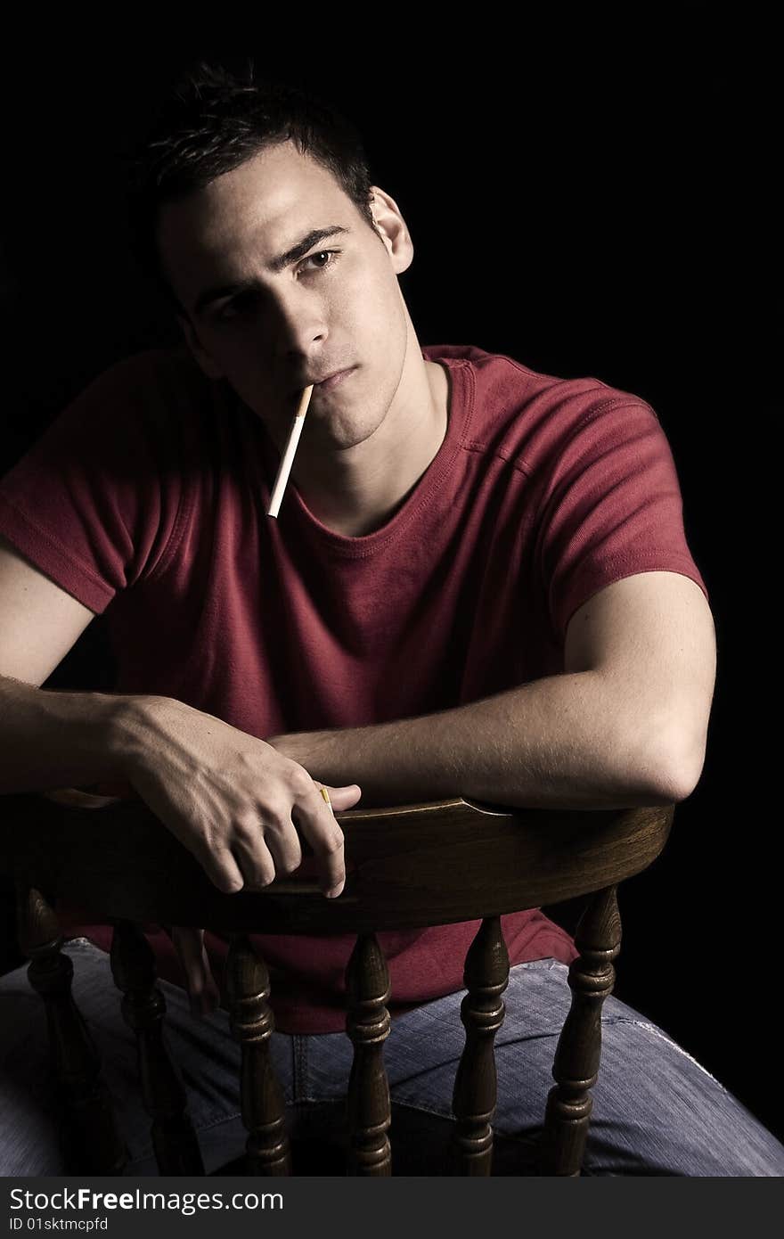 Young handsome guy smoking cigar, isolated on black.