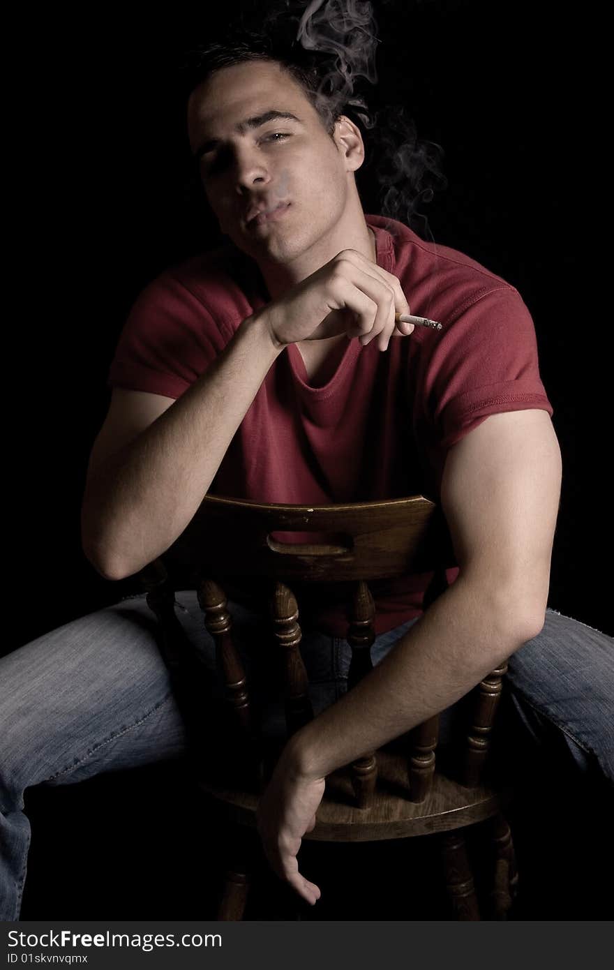 Young handsome guy smoking cigar, isolated on black.