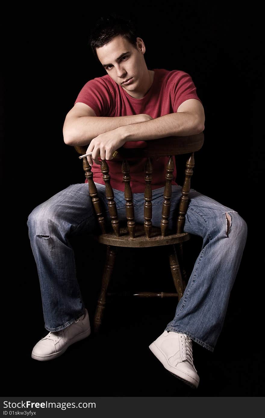 Young handsome guy smoking cigar, isolated on black.