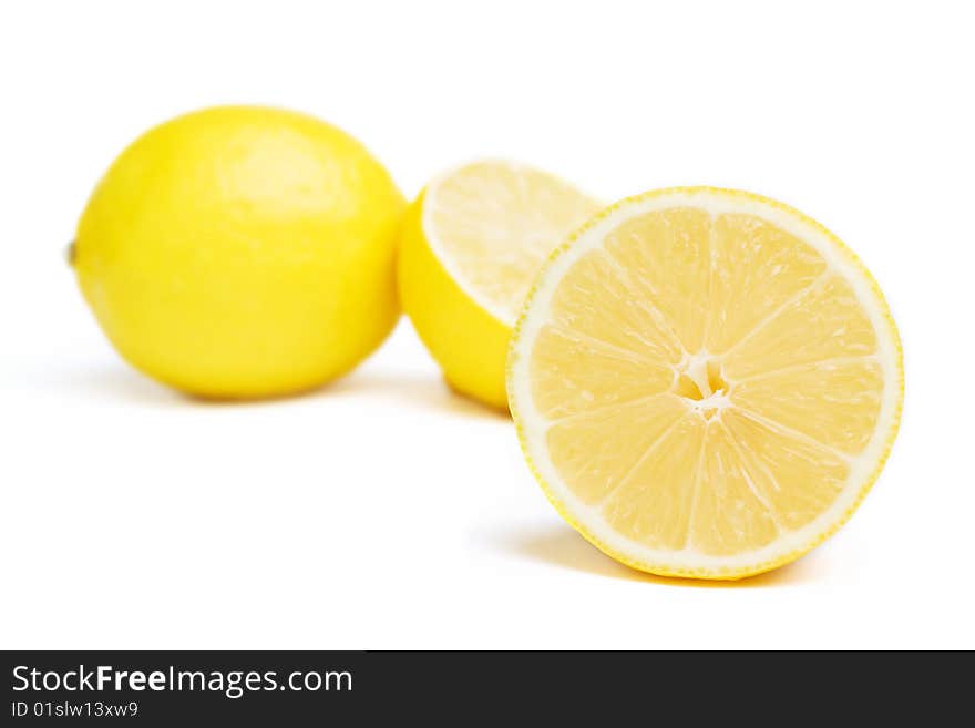 One lemon and two halfs isolated on white. Focus on front lemon. One lemon and two halfs isolated on white. Focus on front lemon.