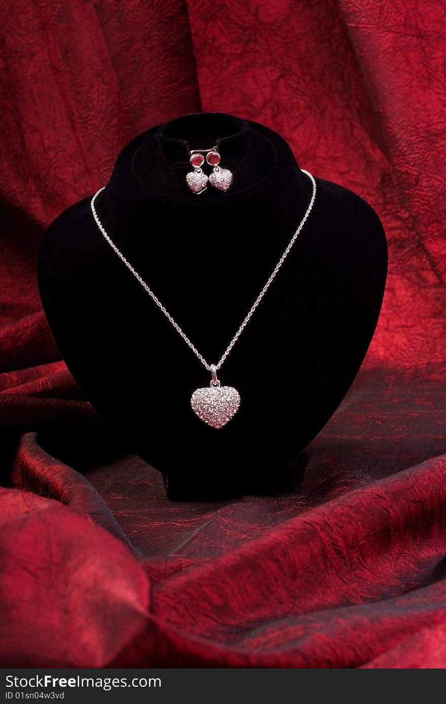 Sophisticated chain with diamond heart and earring on black mannequin