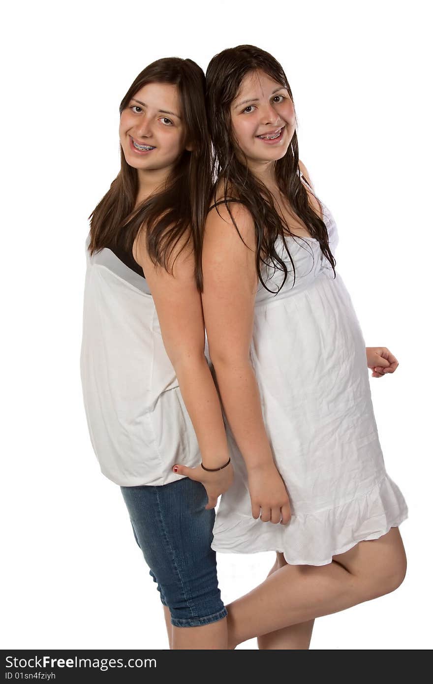 Two identical twin sisters with long brown hair smiling standing over white
