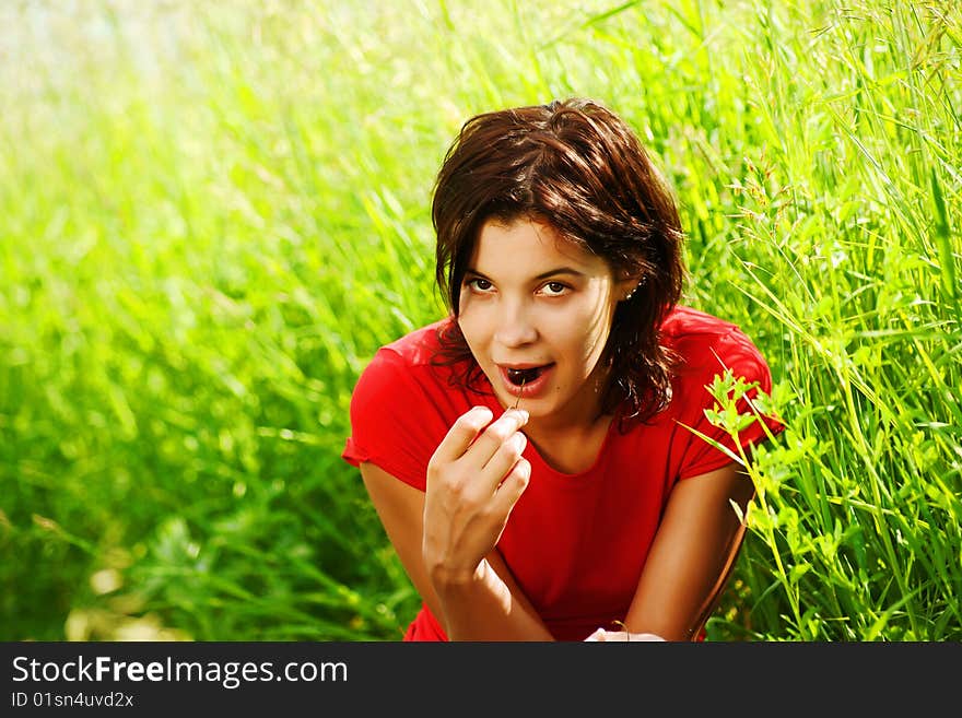 Young beautiful girl with cherries in their hands against a background of grass