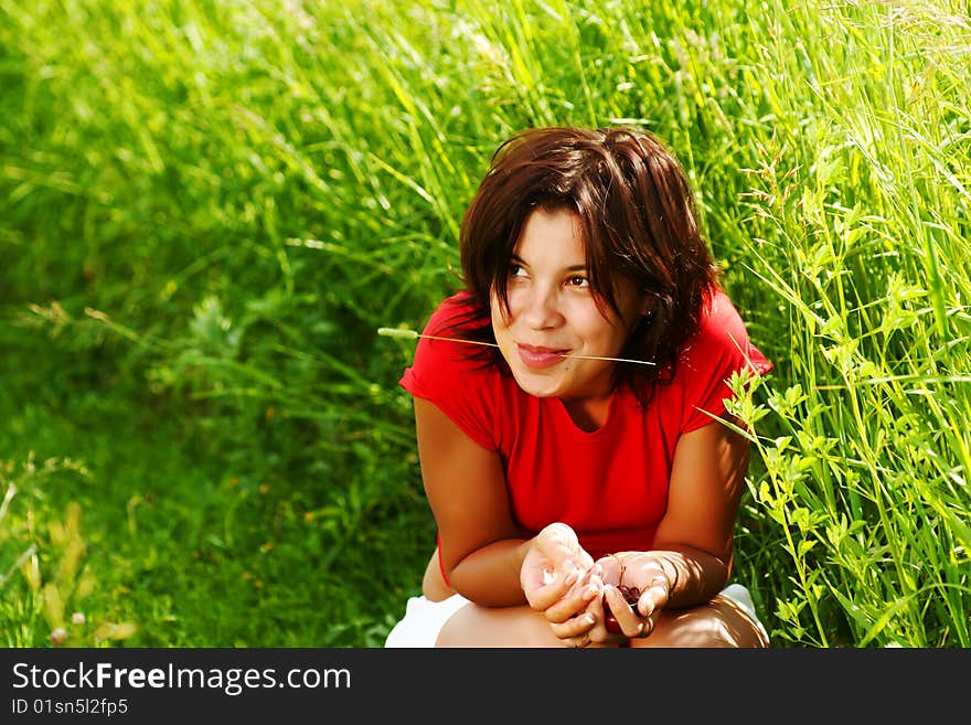 Young beautiful girl with cherries in their hands against a background of grass