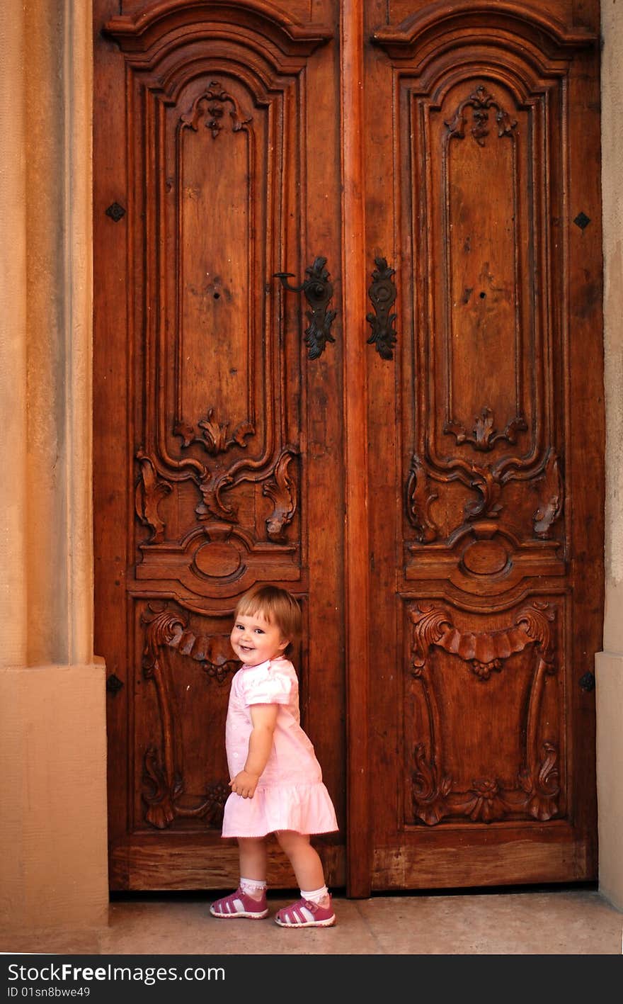 Little girl beating to a closed big door. Little girl beating to a closed big door