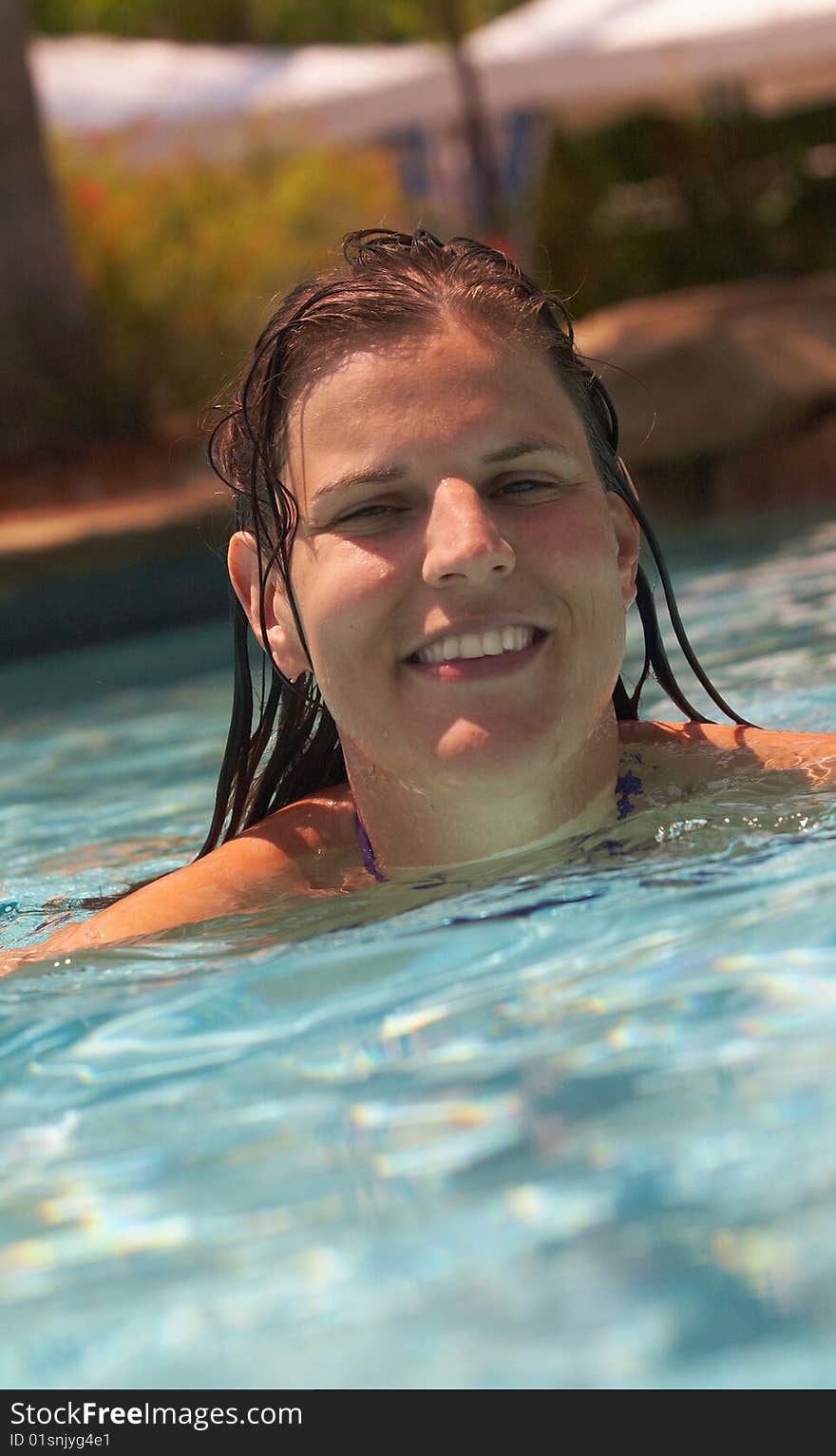 Young woman swimmin in a beautiful pool with palms in the background. Young woman swimmin in a beautiful pool with palms in the background.