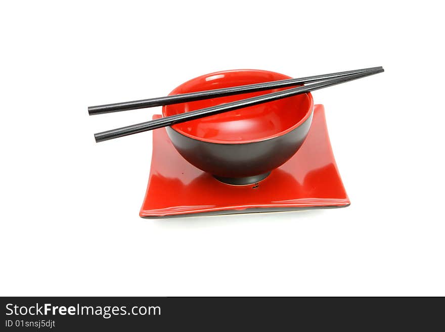 Chopsticks on red and black oriental bowl and square plate isolated