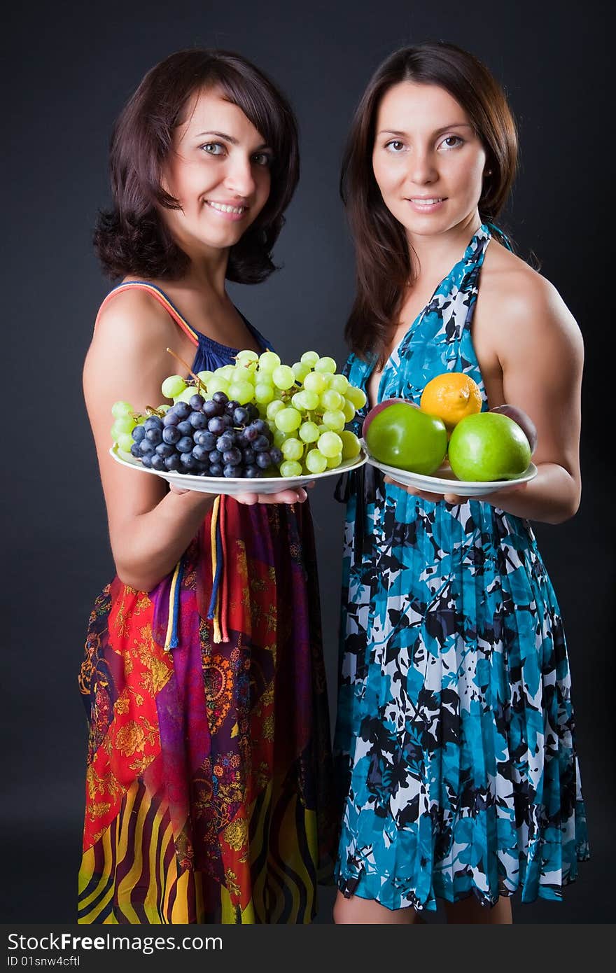 Two beautiful girls hold plates with fruits