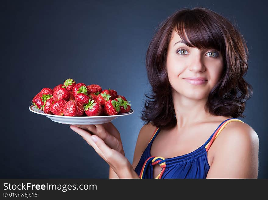 Beautiful girl holds a plate with a strawberry