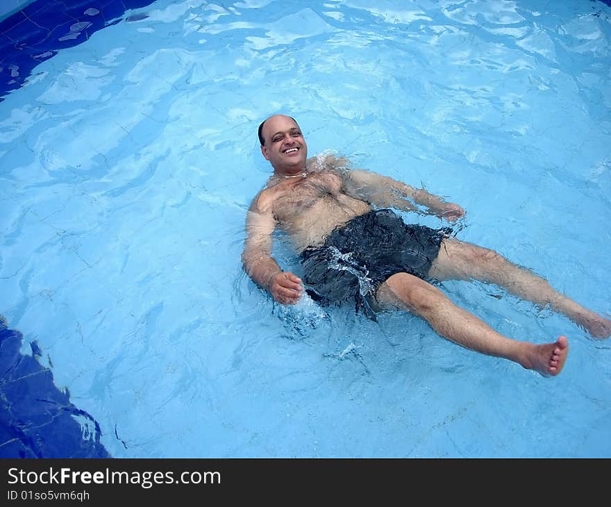 An aged person happily lying in the swimming pool. An aged person happily lying in the swimming pool.