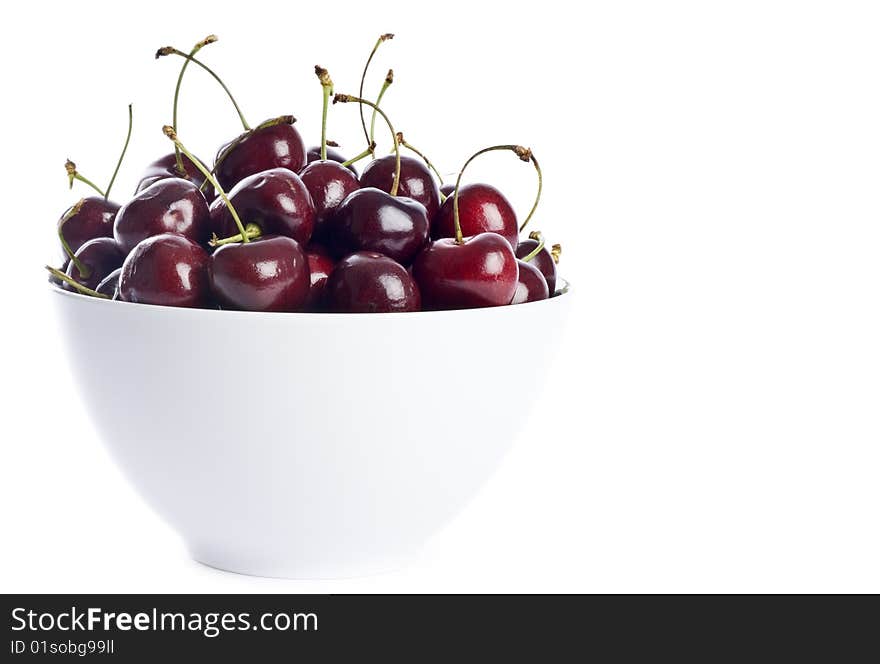 A white bowl full of dark cherries isolated on white. A white bowl full of dark cherries isolated on white.