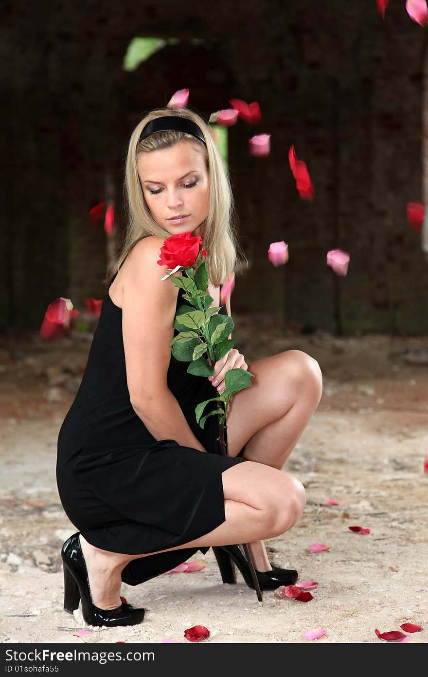 Lovely woman with rose under falling petals