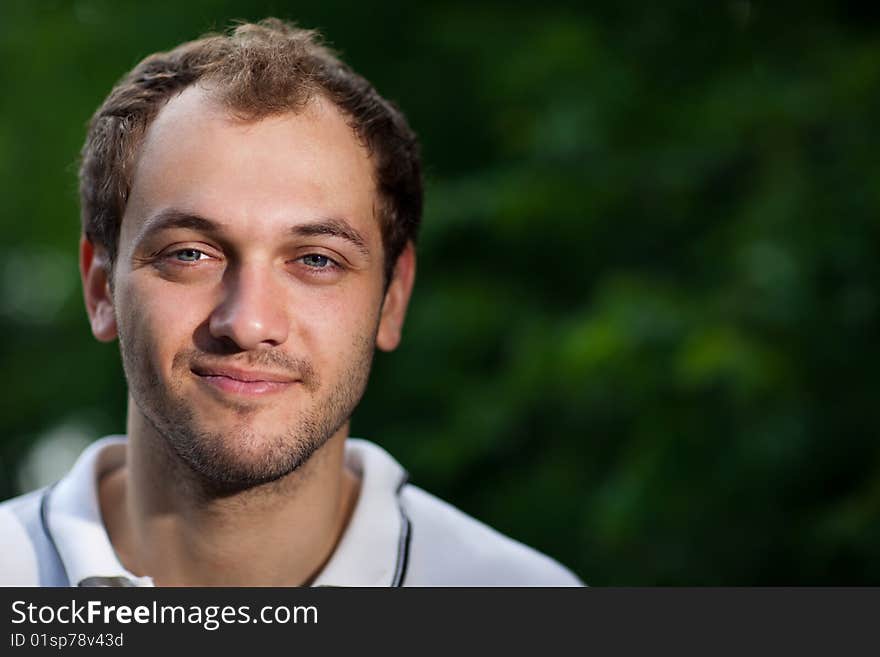 Portrait of a young man on green blurry background - shallow DOF, focus on eyes