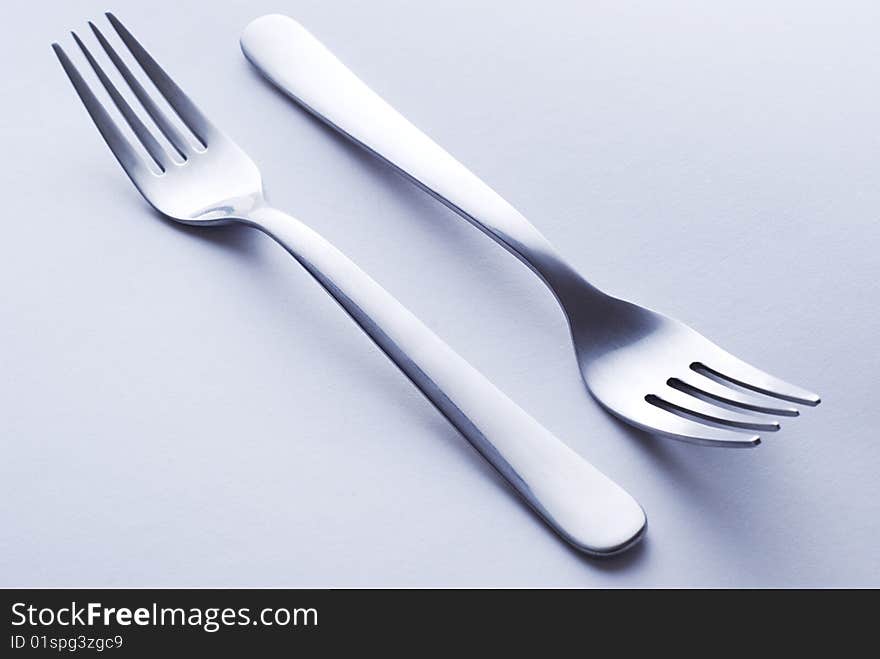 Elegant steel forks on white paper background. Elegant steel forks on white paper background