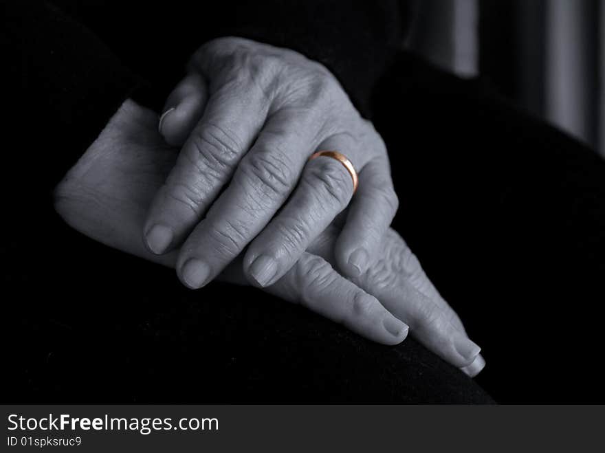 An old lady's hands on her lap in a pensive pose. Idea behind the image is the theme of contemplating time, the passing of many years of marriage accentuated by the gold ring. An old lady's hands on her lap in a pensive pose. Idea behind the image is the theme of contemplating time, the passing of many years of marriage accentuated by the gold ring.