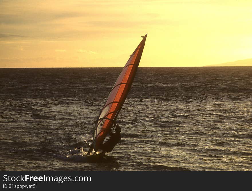 A lone windsurfer at sunset on the Pacific off the coast of Maui. A lone windsurfer at sunset on the Pacific off the coast of Maui.