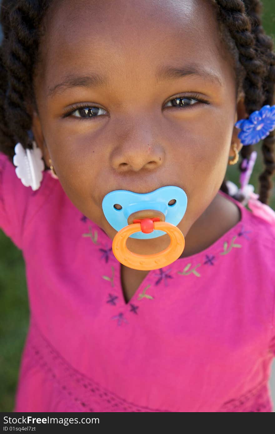 An adorable little african american girl in a pink shirt. An adorable little african american girl in a pink shirt