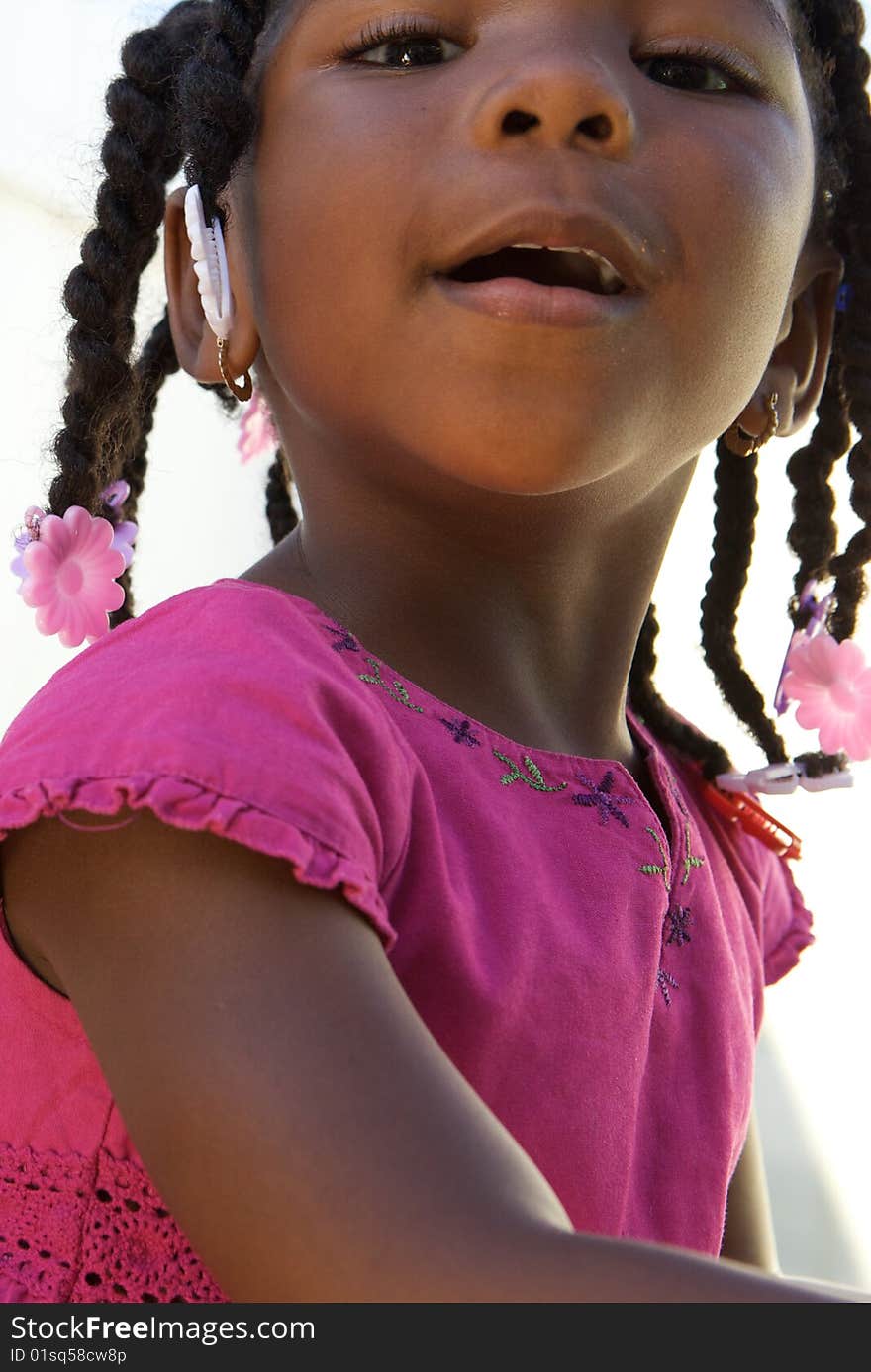 An adorable little african american girl in a pink shirt. An adorable little african american girl in a pink shirt