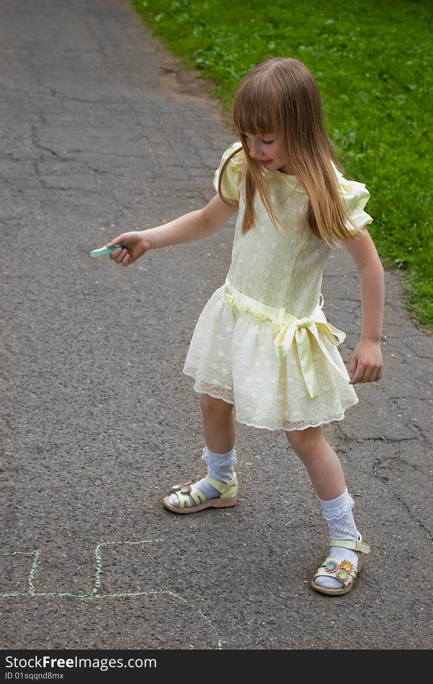 Smiling girl drawing with a crayoun on asphalt. Smiling girl drawing with a crayoun on asphalt