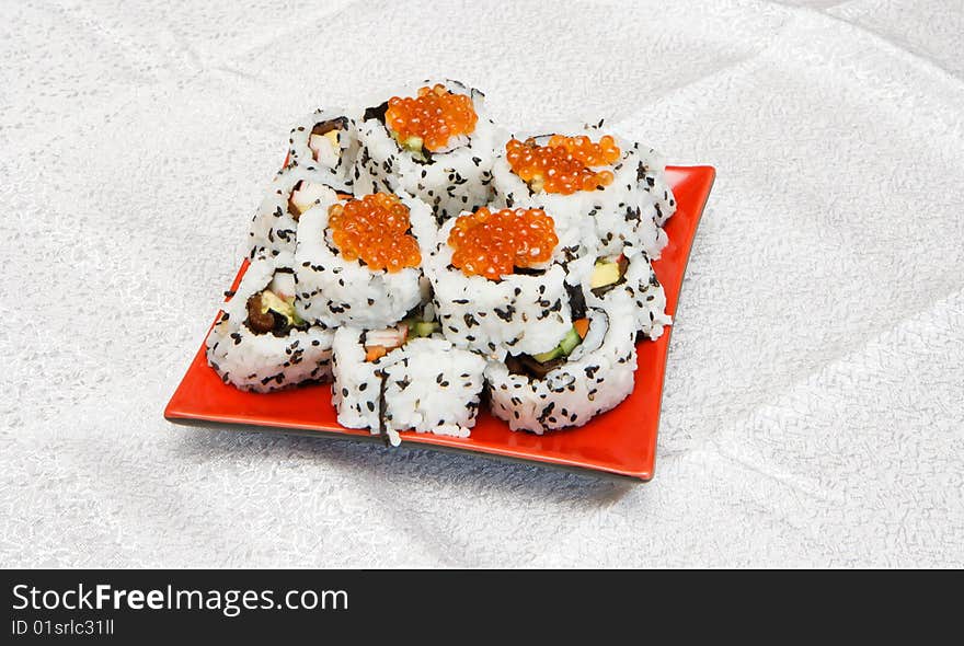 Homemade inside-out maki sushi with red caviar on red square plate. Homemade inside-out maki sushi with red caviar on red square plate