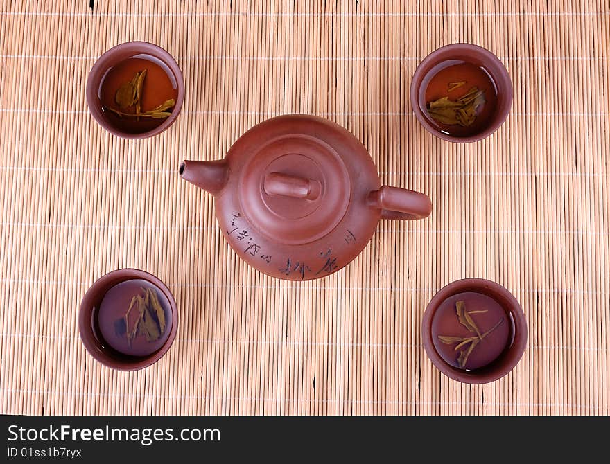 A teapot and four cups of bamboo in the background. A teapot and four cups of bamboo in the background.