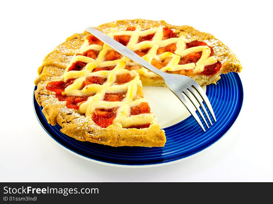 Whole apple and strawberry pie with a small fork on a blue plate with a slice missing on a white background. Whole apple and strawberry pie with a small fork on a blue plate with a slice missing on a white background