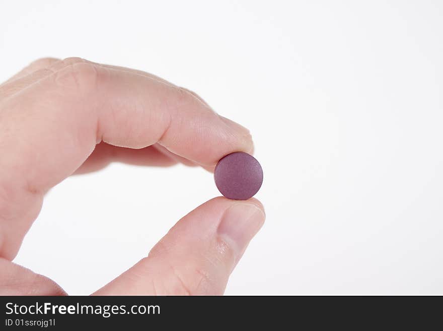 Two fingers holding a single purple round prescription pill. Two fingers holding a single purple round prescription pill