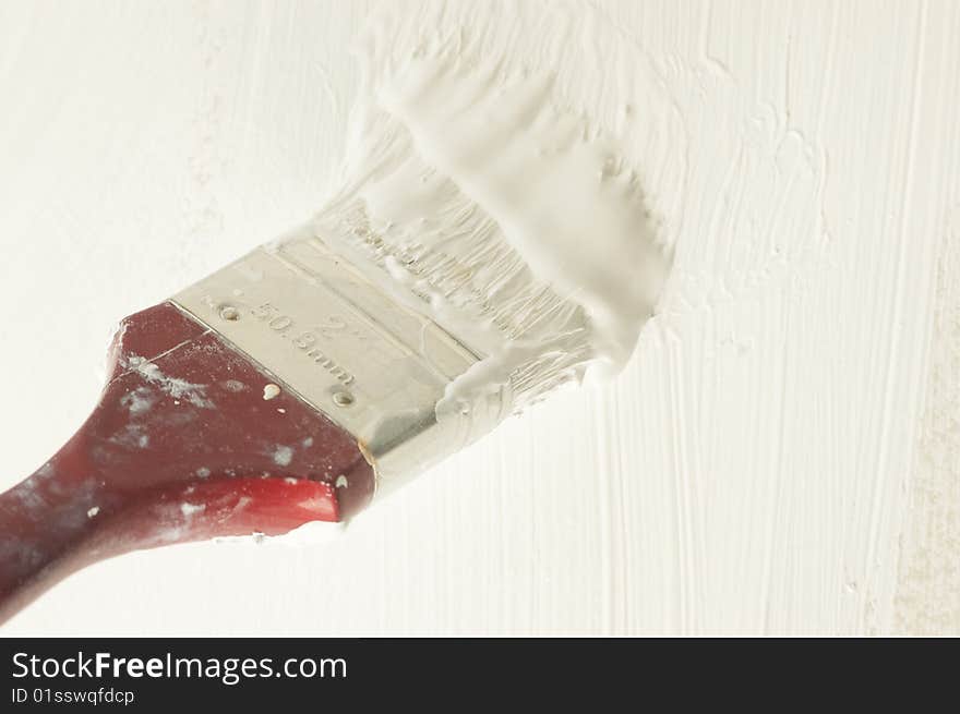 Brush soaked in white paint colouring wall