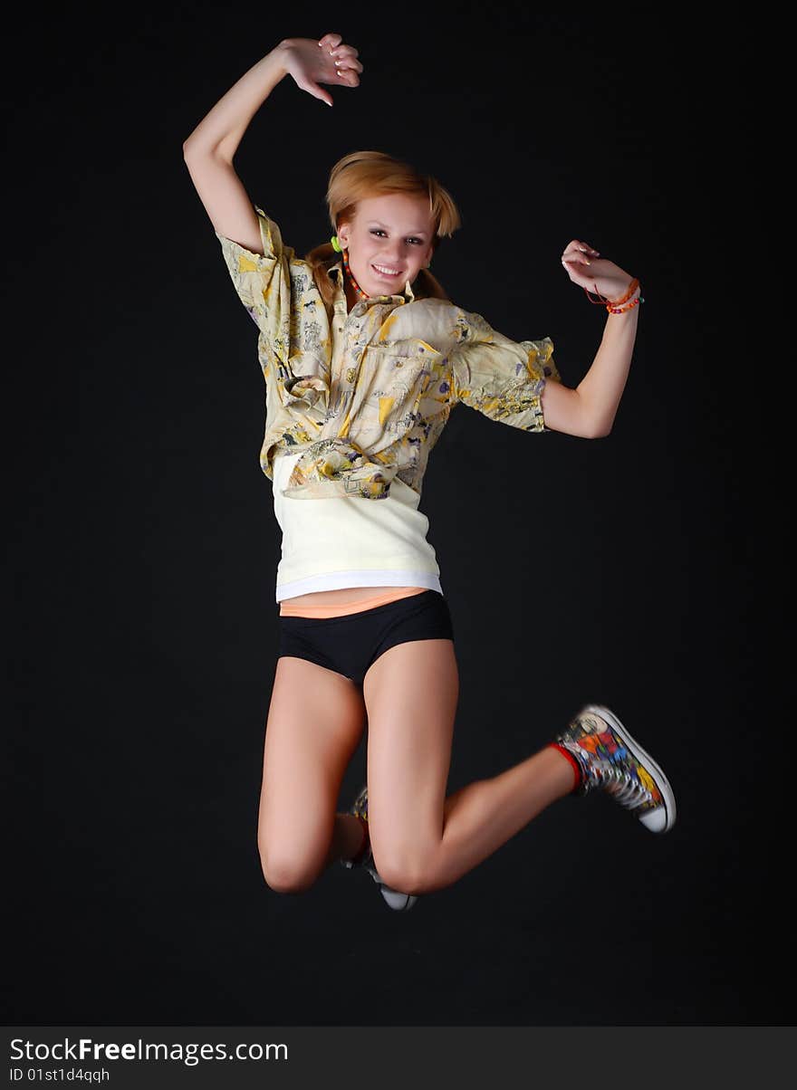 Beautiful young dancer jumping on a black background