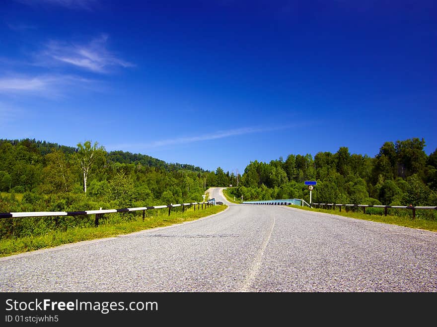 Road with bridge in the woody hills clear sky sunny day nobody