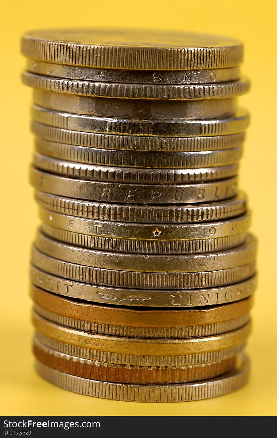 Stacked foreign coins on yellow background