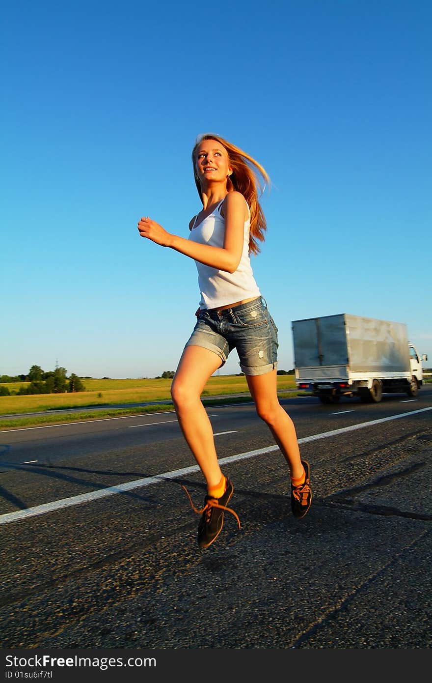 The woman running on road against the sunset sun