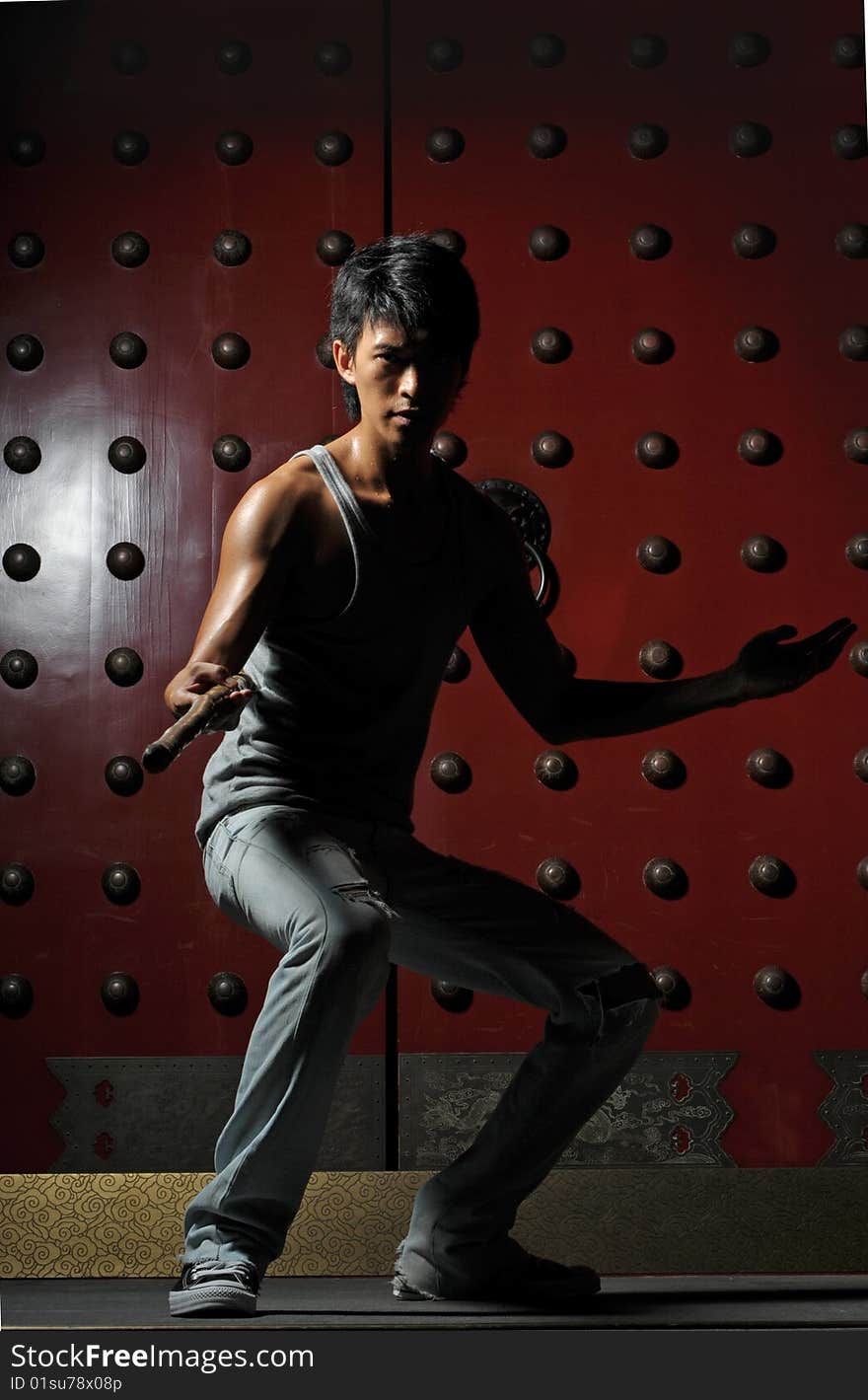 Young Asian Man holding a wooden pole in fighting action in oriental theme. Young Asian Man holding a wooden pole in fighting action in oriental theme.