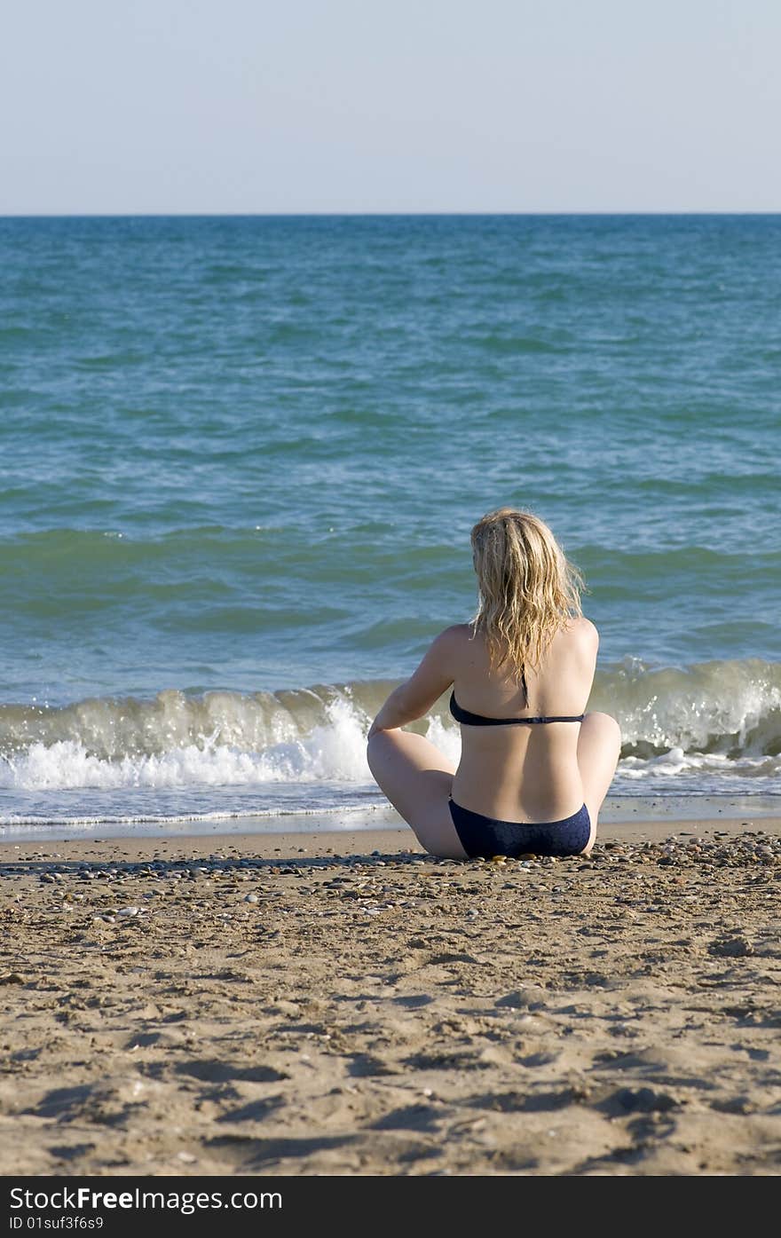 Girl sits on the beach of sea