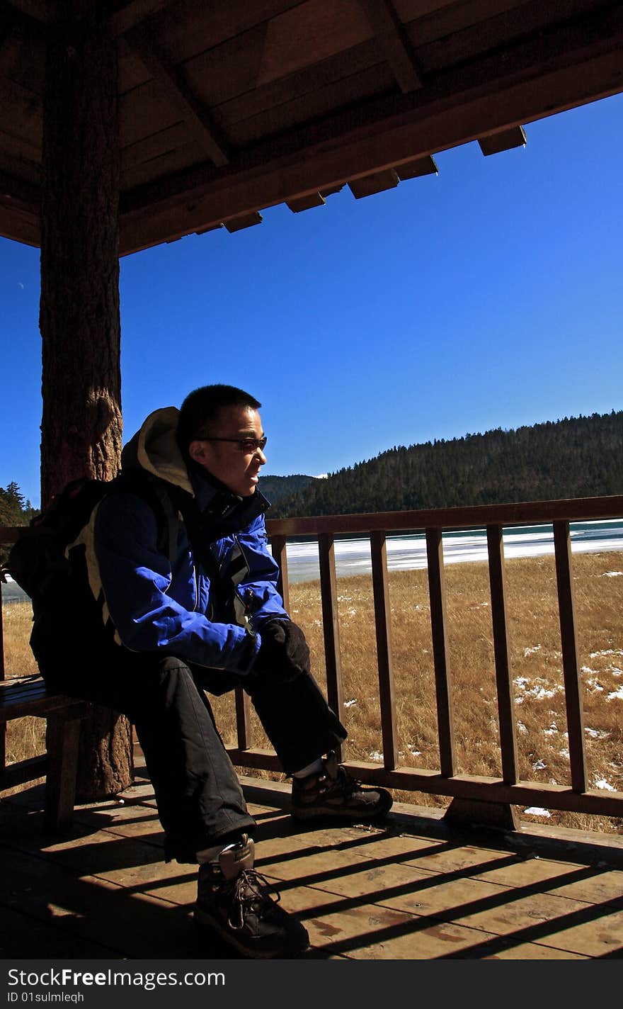 Hiker sitting near the lake and enjoying the sunshine.