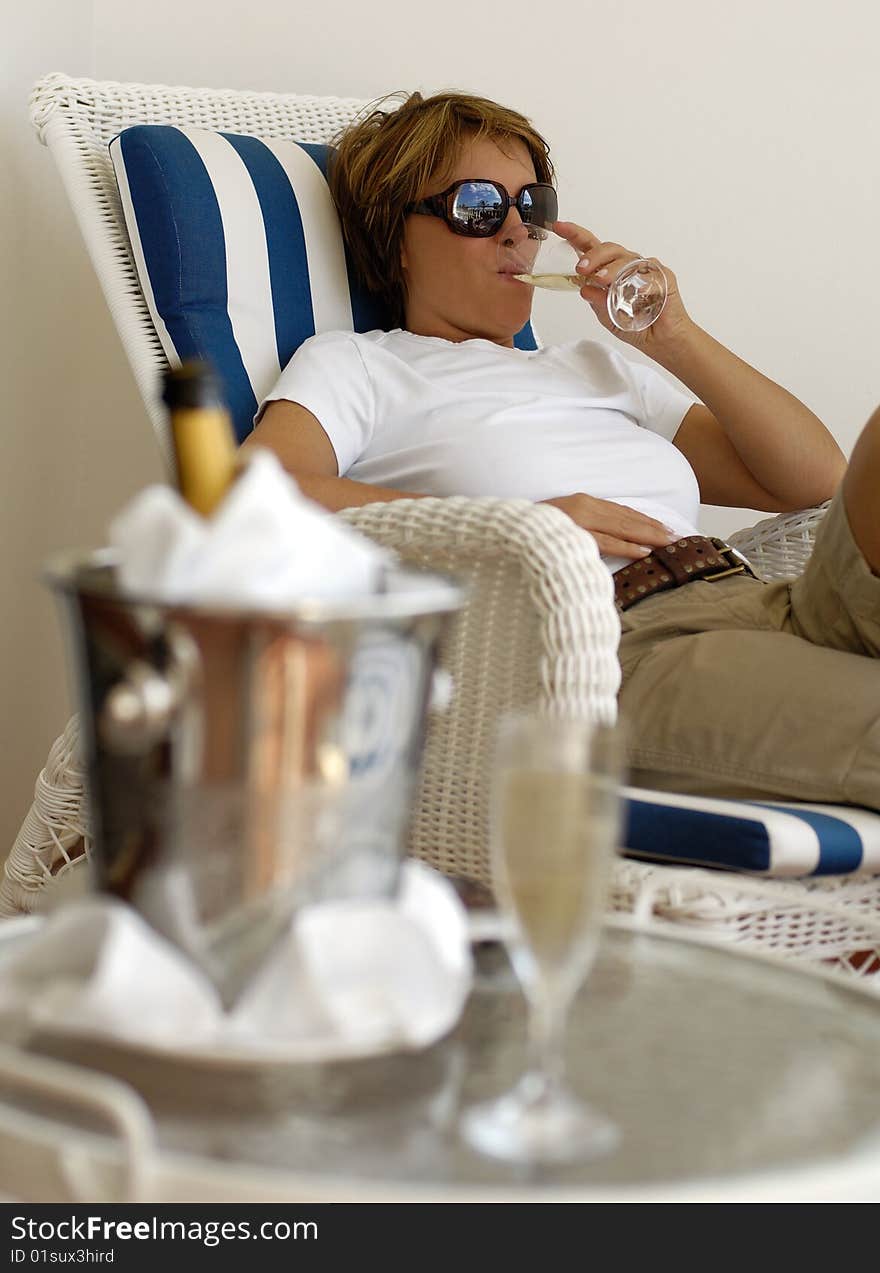 Woman relaxing on a terrasse while drinking Champagne. Woman relaxing on a terrasse while drinking Champagne