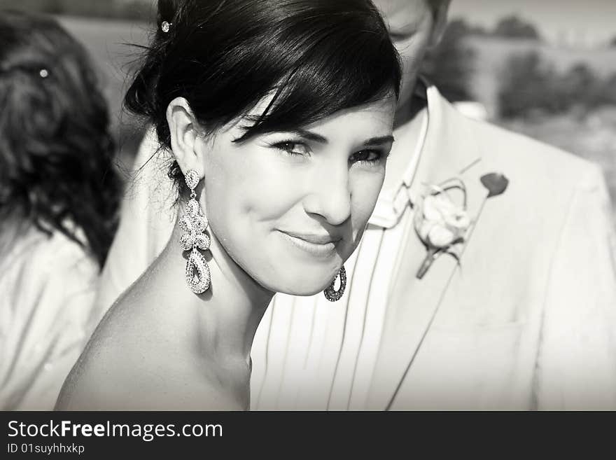 Beautiful brunette bride with hair tied back, her groom in the background. Beautiful brunette bride with hair tied back, her groom in the background