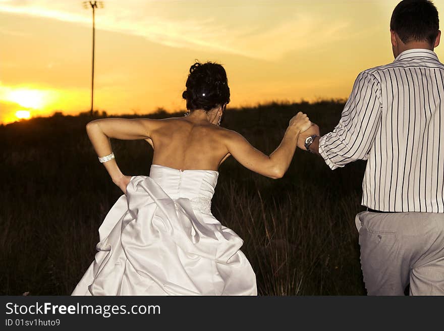 Bridal couple in the field as the sun sets